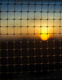 Full frame shot of metal grate against sky during sunset