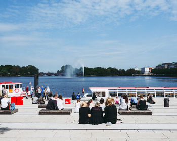 Group of people at riverbank against sky