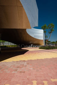 Footpath by building against blue sky