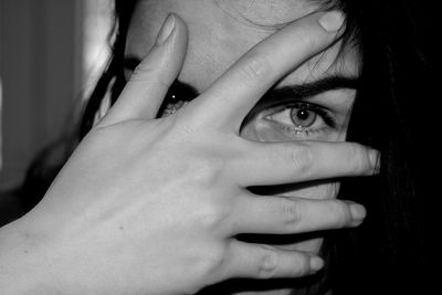 Close-up portrait of young woman hiding face with hand