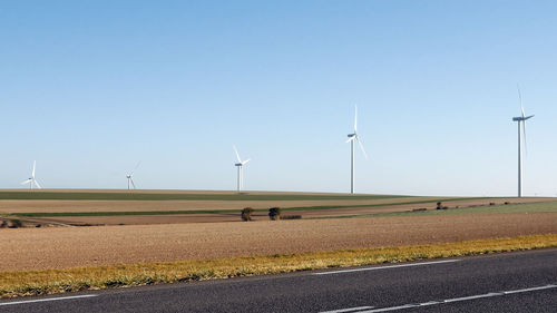 Windmills on field against clear sky