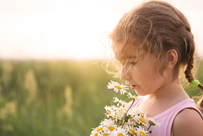 Cute girl holding flowers on field