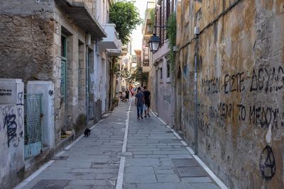 Rear view of people walking on footpath amidst buildings