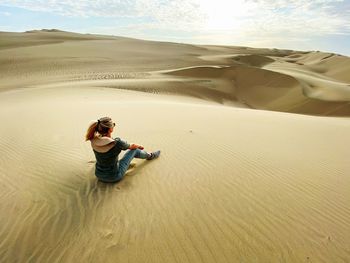 Rear view of woman sitting at desert