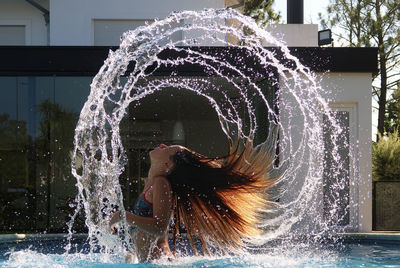 Side view of girl tossing hair in swimming pool