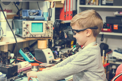 Boy repairing computer part on table at home