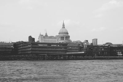 View of buildings by river against sky in city