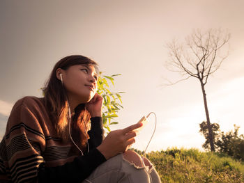 Young woman looking away while sitting on mobile phone