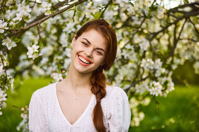 Young woman standing against trees