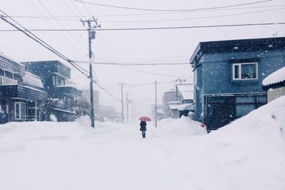 Woman with umbrella walking on snowy street