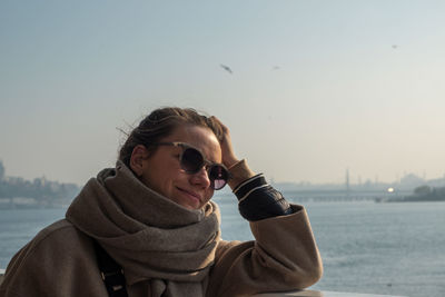 Portrait of young woman standing against sea