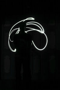 Rear view of silhouette man standing against black background