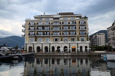 Buildings by river against sky