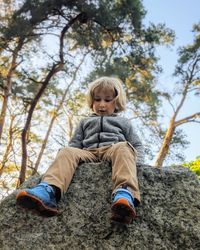 Full length portrait of boy sitting on a rock