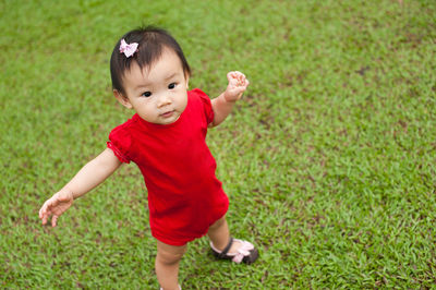 High angle portrait of baby girl standing on grassy field at park