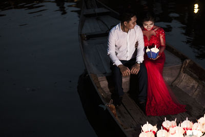 High angle view of couple holding while sitting by water