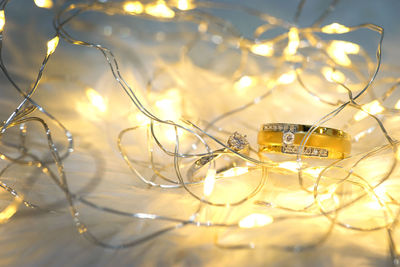 Close-up of engagement rings by illuminated string lights