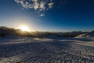 Scenic view of snowcapped mountains against bright sun