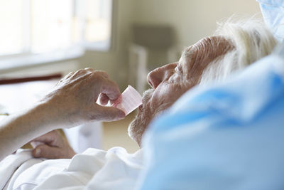 Side view of senior male patient taking cough syrup in hospital ward