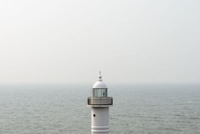 Lighthouse by sea against sky