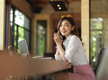 Portrait of smiling young woman using phone