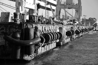 Row of rubber tires hanging from chain by pier in sea at commercial dock
