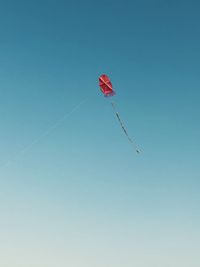 Low angle view of kite flying against clear blue sky