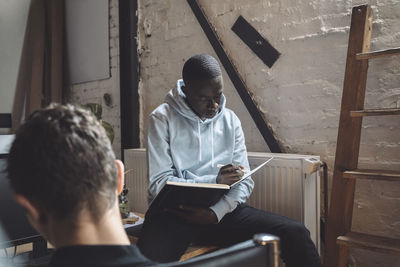 Computer programmer with colleague reading book for coding at workplace