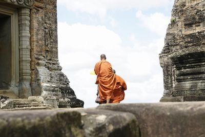 Rear view of statue against temple building against sky