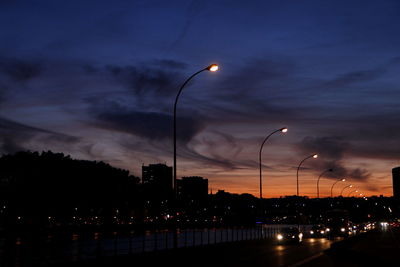 Illuminated street lights against sky at night