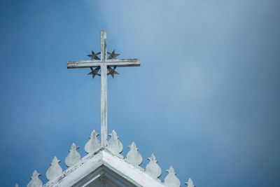 Low angle view of cross sculpture on building against sky