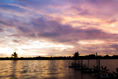 Silhouette boats in sea against orange sky