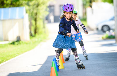 Portrait of girl roller skating through cones on road