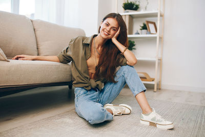 Young woman sitting on sofa at home