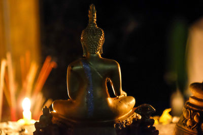 Close-up of buddha statue in darkroom