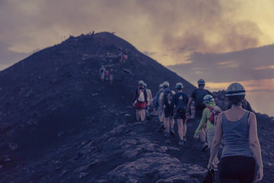 Hikers walking on mountain at sunset