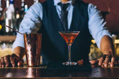 Bartender preparing cocktail at counter in bar