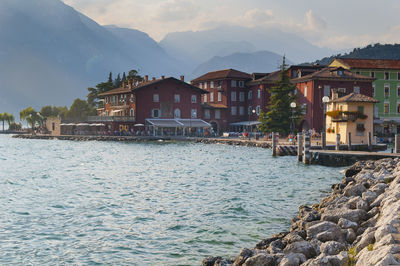Houses by sea and buildings against sky