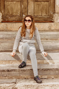 Full length of girl wearing sunglasses while sitting on steps