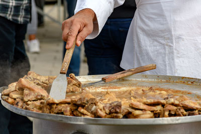 Midsection of chef preparing meat dish in large pot with plate. traditional croatian dish kotlovina