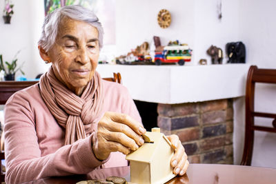 Senior woman inserting coin in piggy bank