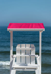 Empty chair on beach against clear sky