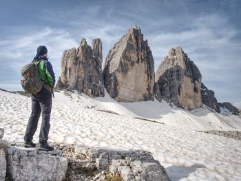 Man trekking in the alps. sharp peaks stick over the clouds in a beautiful sunny day.