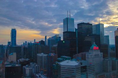 Modern buildings in city against sky during sunset