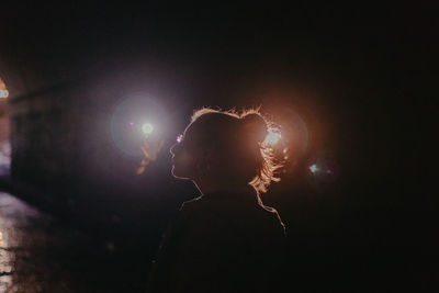 Young woman standing against illuminated lights at night