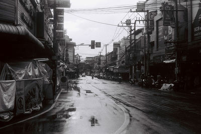 Wet street amidst buildings in city