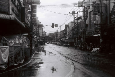 Wet street amidst buildings in city