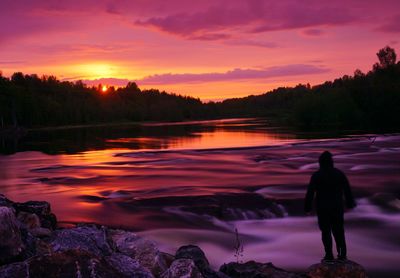 Silhouette man standing by trees against sky during sunset