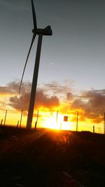 Silhouette windmill on landscape against sky during sunset