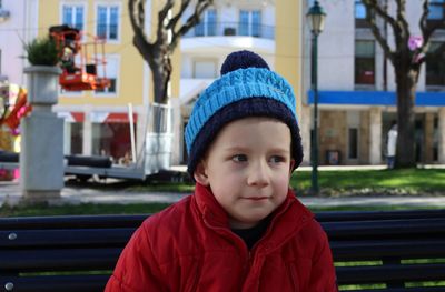 Portrait of a shy boy in a blue hat and red jacket.a six-year-old boy purses his lips and looks away